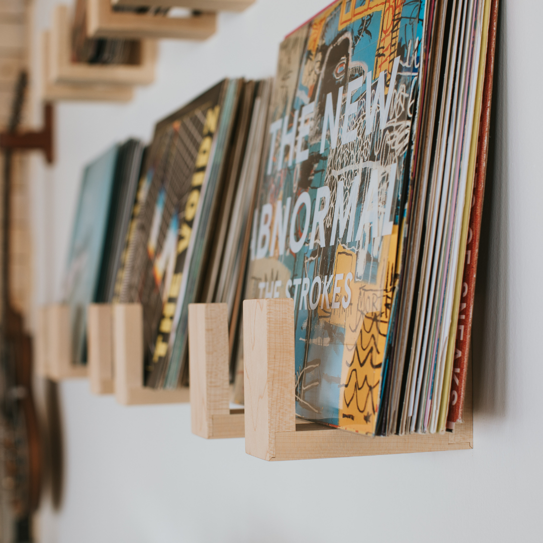 Records sitting in wall mounted wooden racks displaying them front-facing